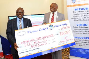 MKU Vice Chancellor Prof. Stanley Waudo presents a dummy cheque of 10 million to the Chairman of the organizing committee of the first ever International Conference on Peace, Security and Social Enterprise, Dr. Vincent Gichuru Gaitho last September.